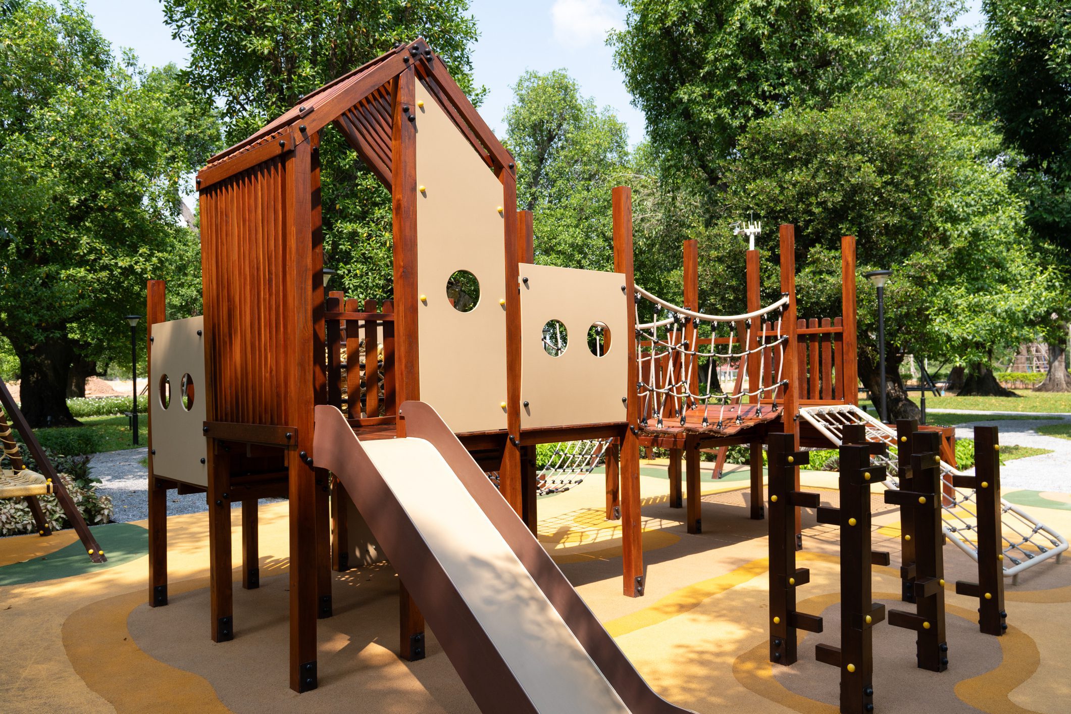 Wooden playground structure with slide and rope bridge
