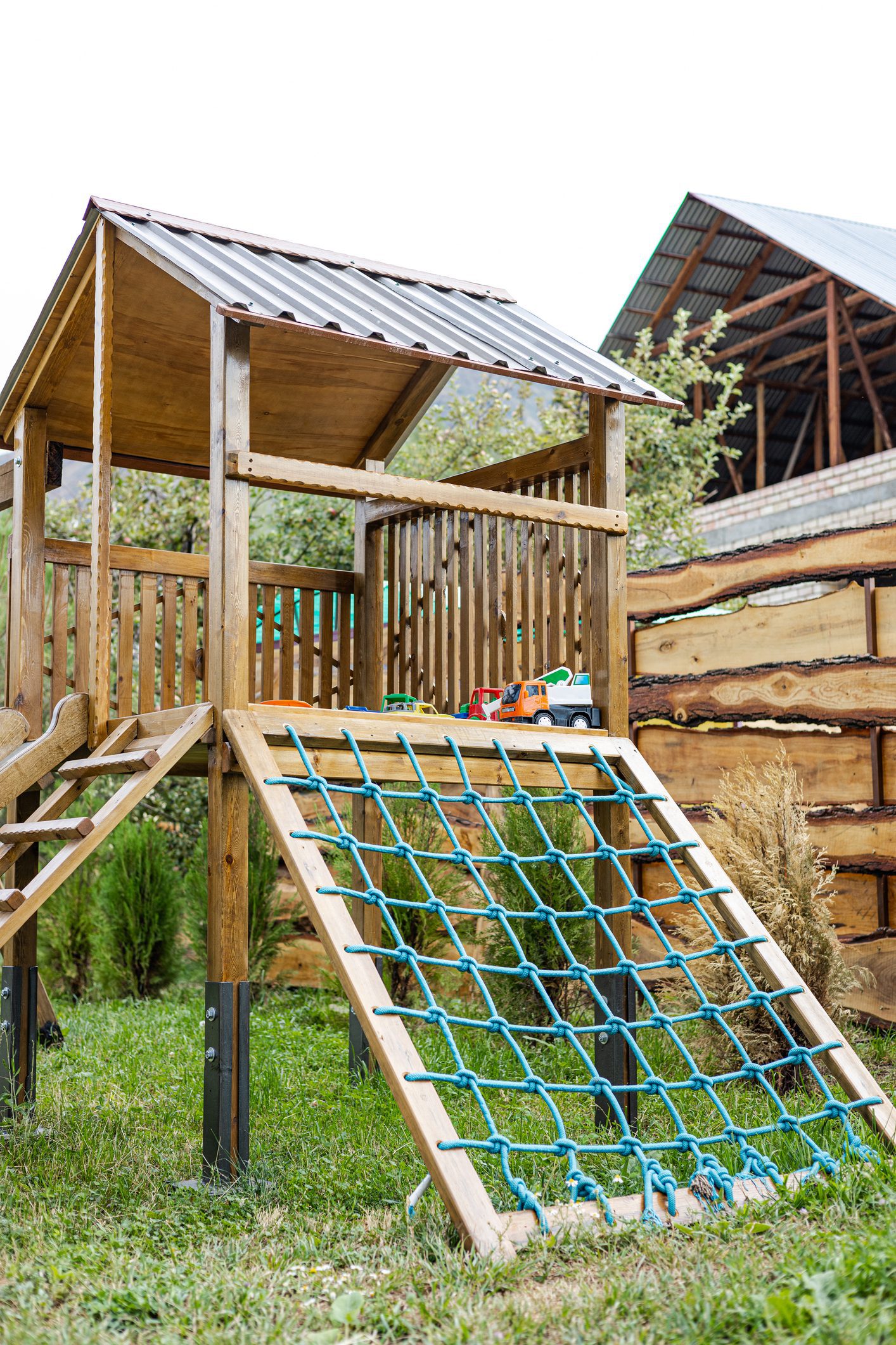 Wooden backyard playhouse with climbing net